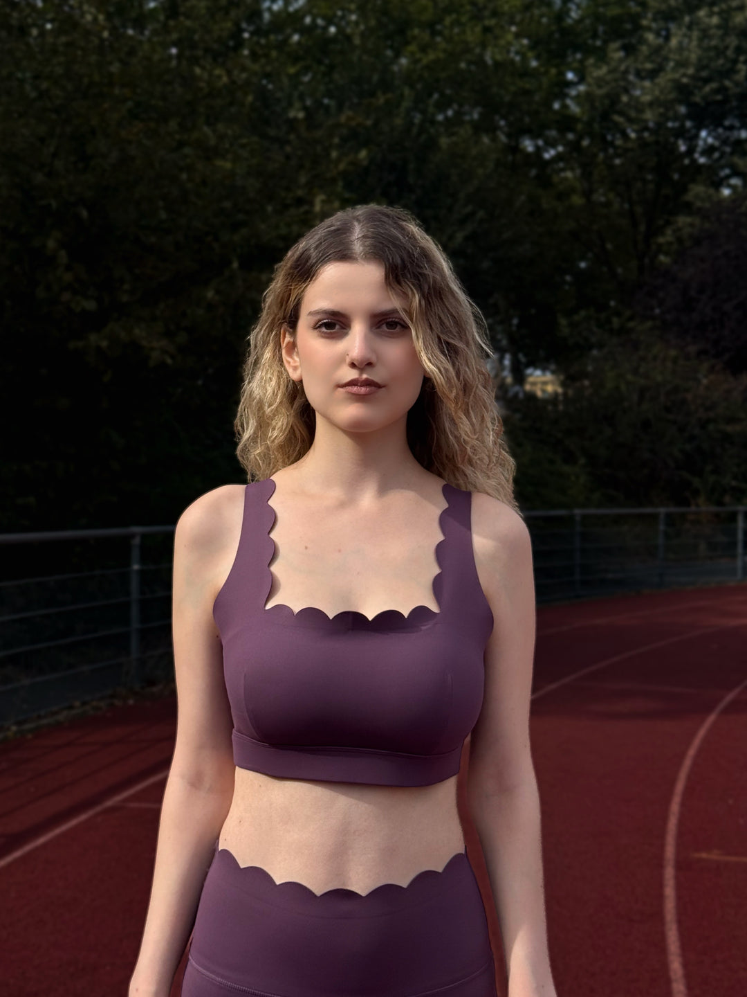 Woman wearing a purple top with scalloped edges on a track field